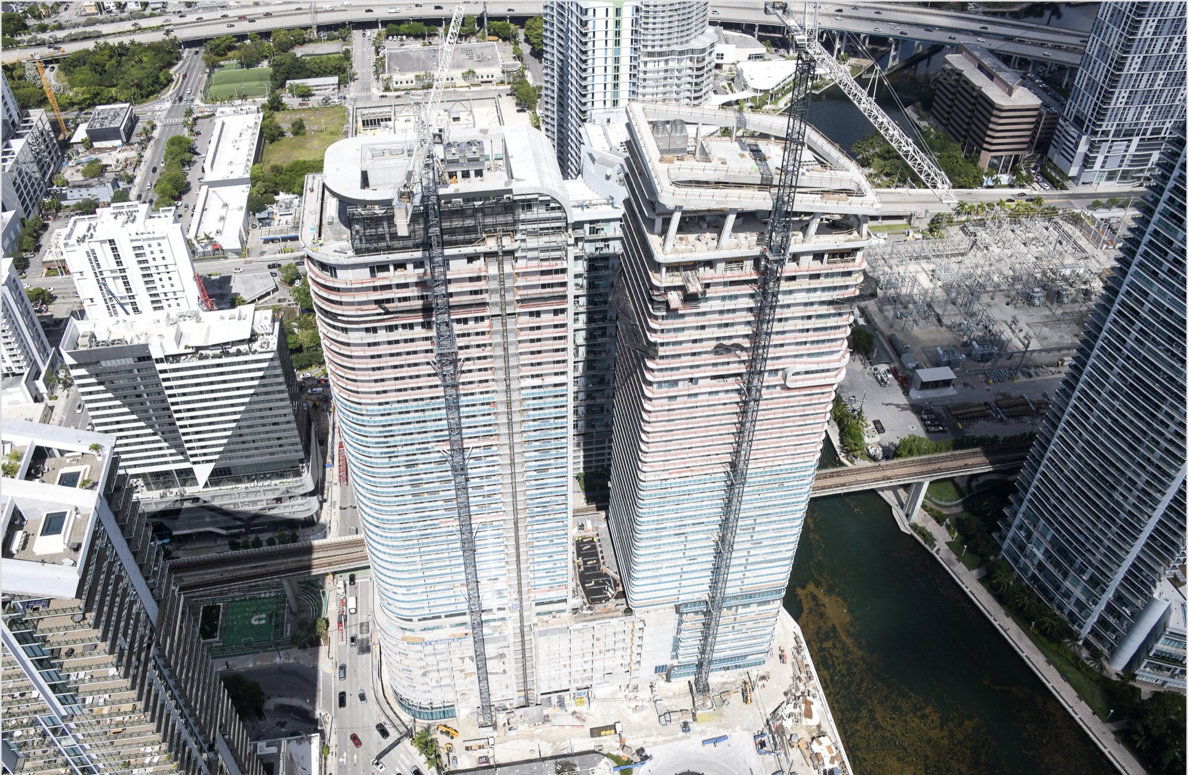 Construction aerial, May 2026: the tower beside the Miami River and The Underline